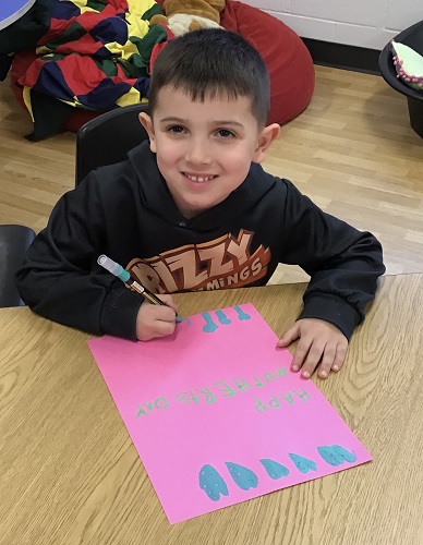 A child making a Mother's Day card at the table