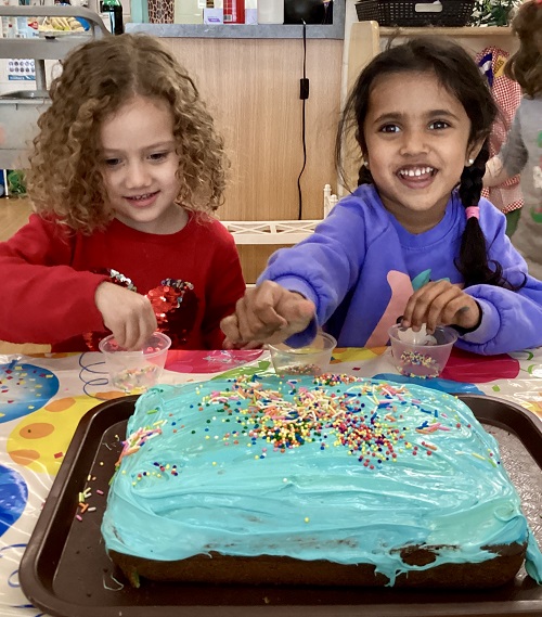 2 preschool children decorating a birthday cake