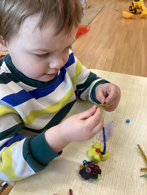 A child examining the sparkly pipe cleaner in their hand.