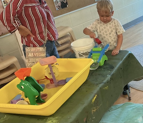 Preschool child pouring water into a balance scale