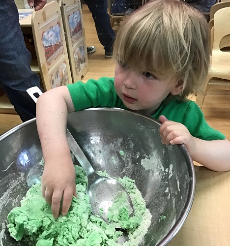 A child playing with playdough in a large bowl