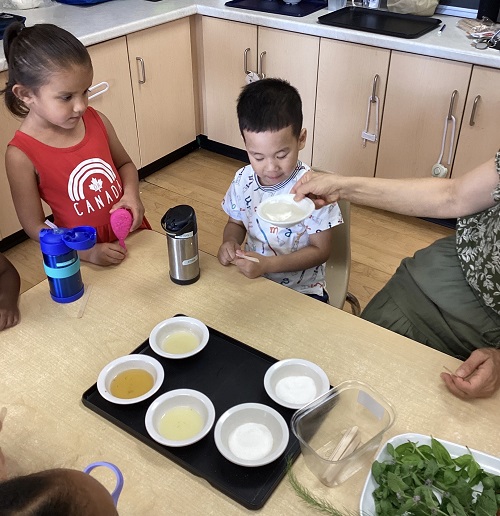 children sitting at a table to taste test different food items
