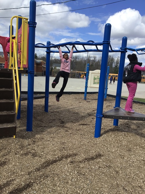 Child swinging on monkey bars.