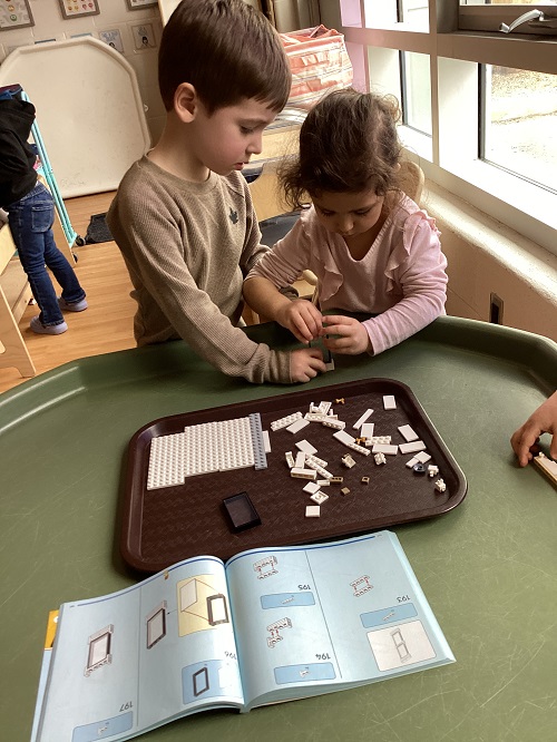 2 preschool children working together to build with lego