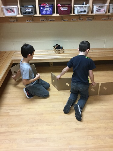 2 boys using up cardboard to create a structure