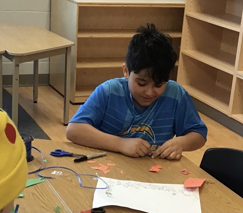 A child putting glue on a small piece of paper