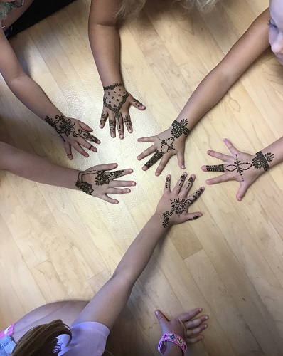 Five children showing their completed henna designs