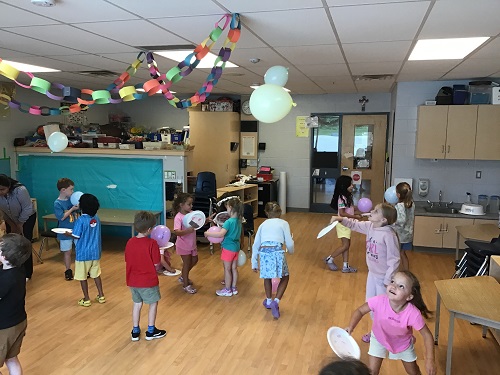 Summer camp children engaged in balloon tennis